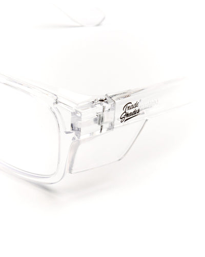 Close-up detail of Trade Shades clear frame safety glasses hinge, temple and Trade Shades logo